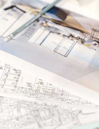 Close-up of architectural blueprints and 3D design on paper with pencil on a desk.